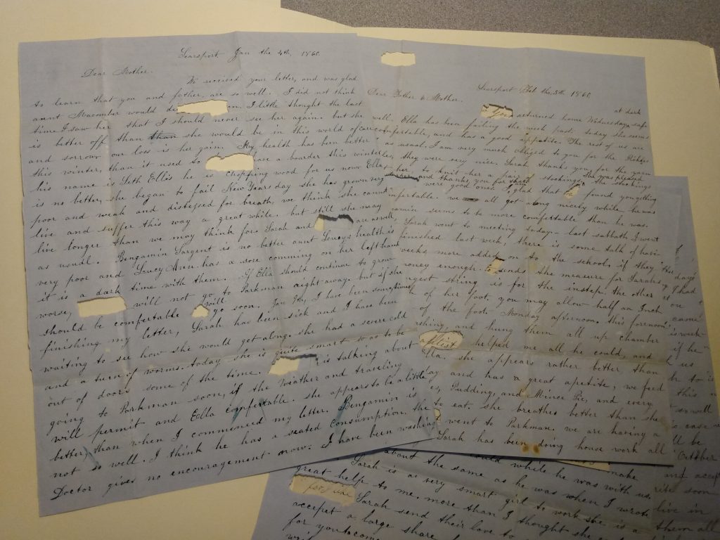 Color photograph of several black ink handwritten letters spread out in a messy layer. Each one has ovals or rectangles ripped out, the size of one word or one letter. The papers are folded, dirty, and discolored with age. 