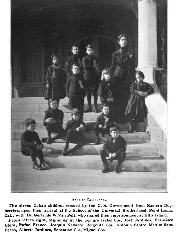 Black and white photograph of a white woman with dark hair and eleven Cuban children of various ages in various positions on the front steps of a large building. Four of the children are seated at the front, and the rest are standing. All of them wear dark clothing. At the right of the image is a large white pillar, and at the back is the door into the building. The caption at the bottom begins with the heading: “Safe in California.”