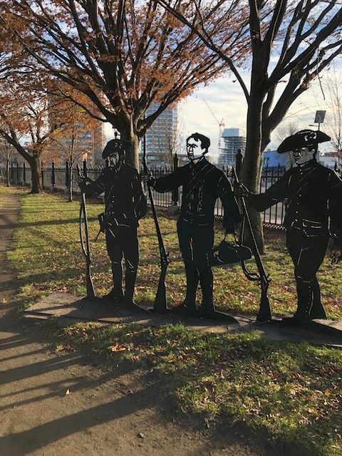 Photo of 3 cut-out statues standing in a park-like environment