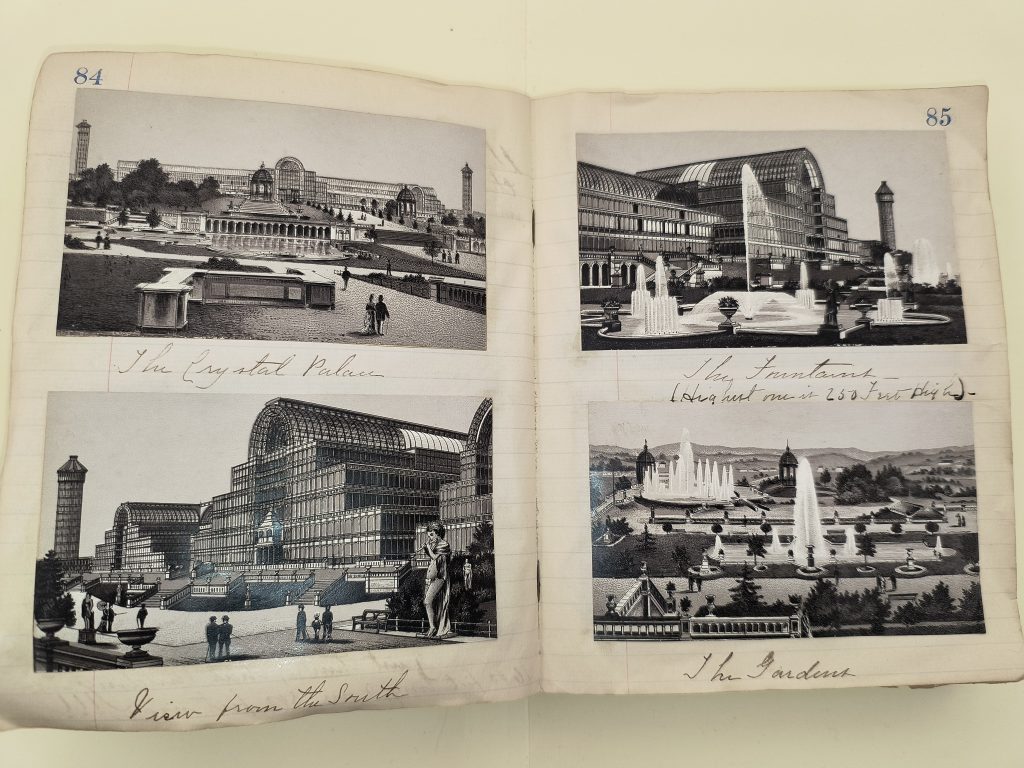 Color photograph of two pages of an open volume, numbered 84 and 85, with two black and white prints pasted onto each page. The prints show a large glass building from multiple angles, some with fountains or people in the foreground. Underneath the prints are the following captions written in black ink: “The Crystal Palace,” “The Fountains,” “View from the South,” and “The Gardens.”