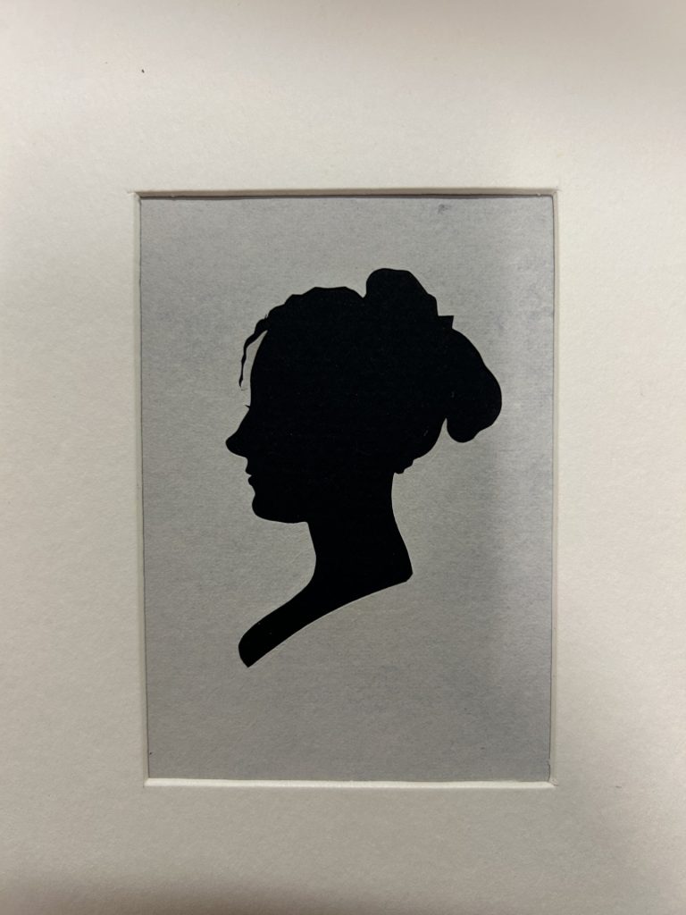 Profile of woman with her hair up in a black silhouette on white paper