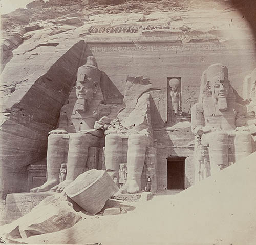 View of Abu Simbel including a man (a dragoman) standing next to the feet of one colossus of Ramses II Photograph View of Abu Simbel including a man (a dragoman) standing next to the feet of one colossus of Ramses II Photograph