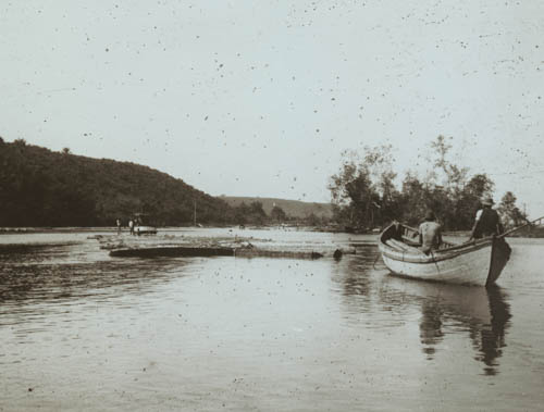 Launch towing raft; surf, boat behind Lantern slide